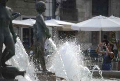 Una mujer fotografia una fuente de Valencia.