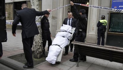 Empleados de la funeraria trasladan el cuerpo del hombre fallecido.