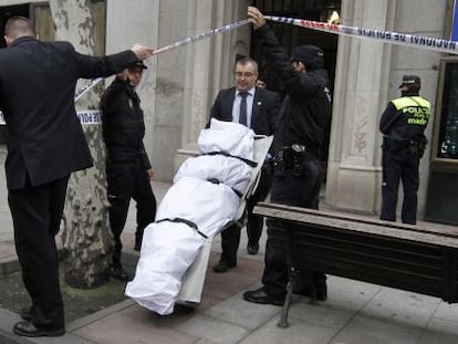 Empleados de la funeraria trasladan el cuerpo del hombre fallecido.