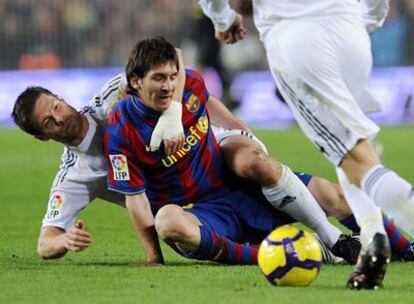 Messi, en el suelo, agarrado por Xabi Alonso tras una entrada del centrocampista madridista.