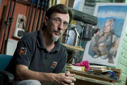 Ruben López en el taller de su padre Julio, con un retrato de éste.