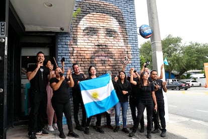 Staff at Miami’s Fiorito Restaurant wave the flag of Argentina in front of a mural of Lionel Messi