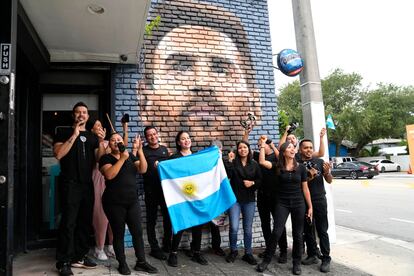 Staff at Miami’s Fiorito Restaurant wave the flag of Argentina in front of a mural of Lionel Messi