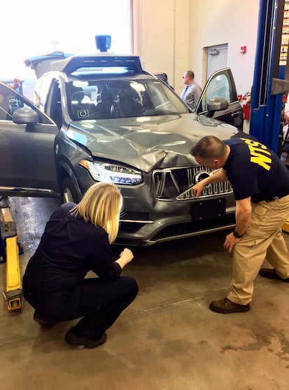 In this photo provided by the National Transportation Safety Board, investigators examine a driverless Uber SUV, March 20, 2018, that fatally struck a woman in Tempe, Ariz. 