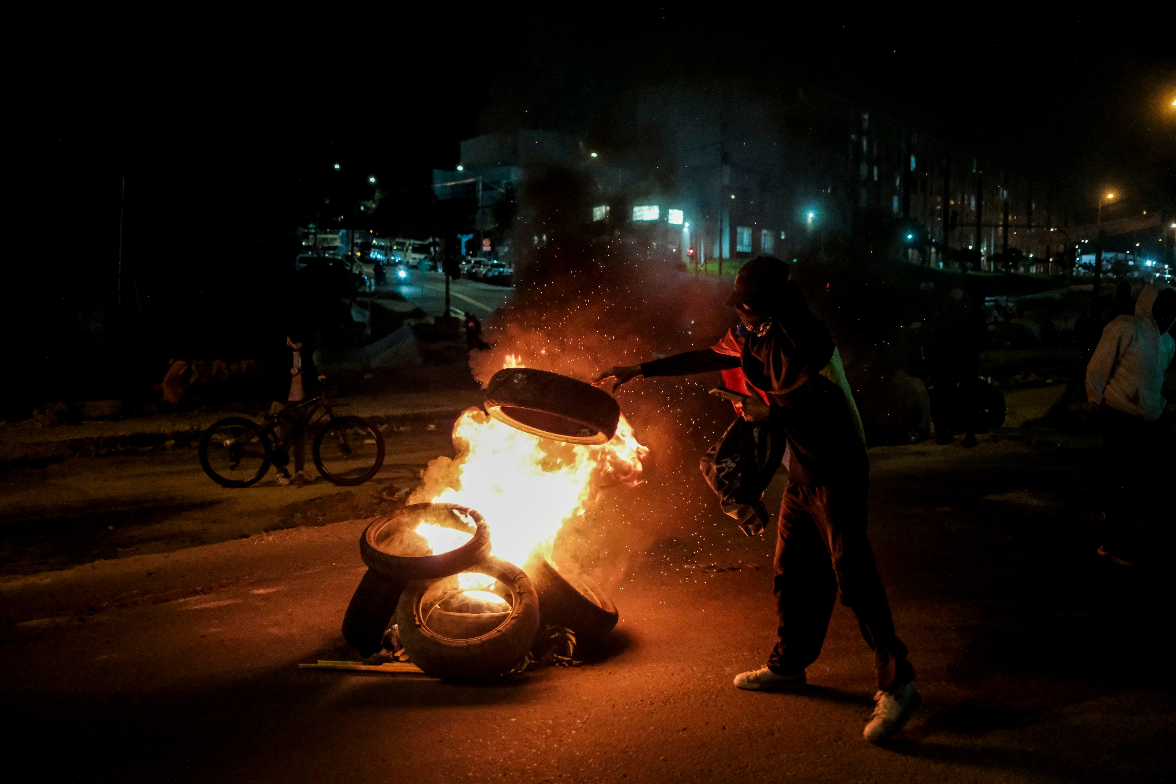 Un manifestante arroja llantas a una hoguera para intensificar los bloqueos de las calles, carca al Portal de Las Américas, en Bogotá, el 28 de Mayo del 2025.
