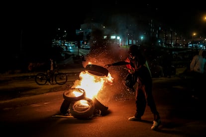 Un manifestante arroja llantas a una hoguera para intensificar los bloqueos de las calles, carca al Portal de Las Américas, en Bogotá, el 28 de Mayo del 2025.