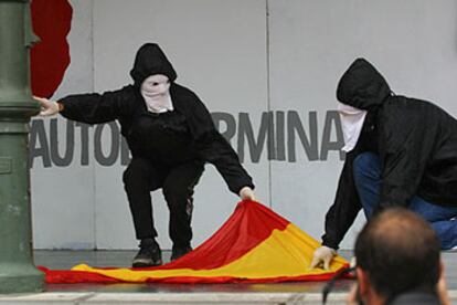 Dos encapuchados se preparan para quemar la bandera española en la manifestación del domingo en San Sebastián.