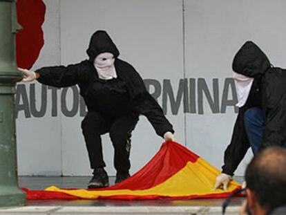 Dos encapuchados se preparan para quemar la bandera española en la manifestación del domingo en San Sebastián.