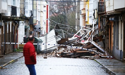 Un hombre observa una calle cortada tras el derrumbe por las lluvias de una fachada de un edificio abandonado este martes, en el barrio de Esteiro, en Ferrol (A Coruña).