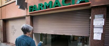 Una boticaria cierra su farmacia en la calle Guardiola i Felip para protestar por los 416 que les adeuda la Generalitat.