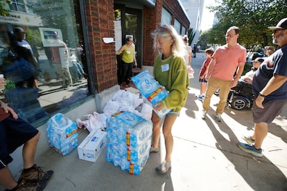 Voluntarios y empleados del gobierno local recogen botellas de agua antes de distribuirlas a los residentes mientras la ciudad permanece sin servicios de agua después del huracán 'Helene', en Asheville.