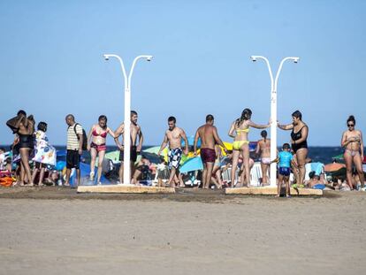 Un grup de banyistes es dutxa en una platja de València