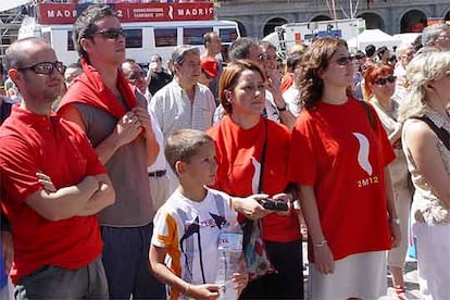 Un grupo de vecinos de diferentes edades contemplan la pantalla instalada en la Plaza Mayor, decepcionados con el no a Madrid 2012.