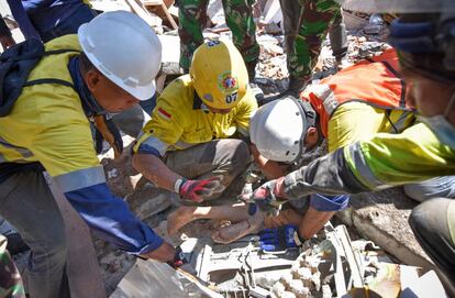 Trabajadores rescatan con vida a una mujer atrapada entre los escombros, el 7 de agosto de 2018 en Tanjung. 