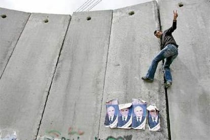 Un palestino escala el muro israelí en la localidad de Abu Dis, fronteriza con Jerusalén.