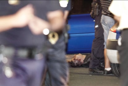El atracador, abatido por la policía, yace en el suelo.