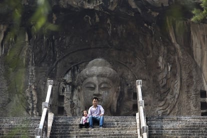 Un padre y su hija, sentados en las escalera de piedra que conducen a la estatua del Buda Vairocona en el Templo Feng Xian (China), el 22 de septiembre de 2014.