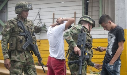 Military police search two young men.