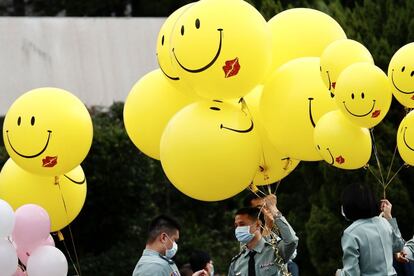 Varios oficiales llevan globos con caritas sonrientes durante la boda.