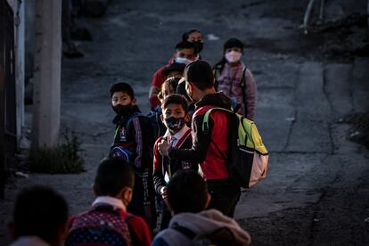 Un grupo de alumnos de la escuela primaria Adolfo López Mateos en la Colonia La Magdalena Chichicaspa, Estado de México, esperan en fila para entrar al colegio, el 8 de marzo de 2022.