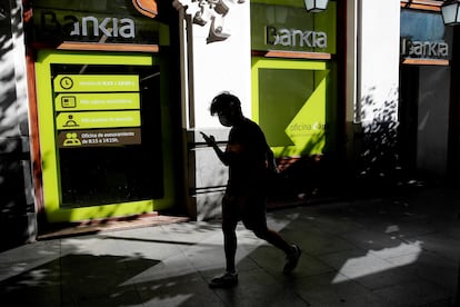 Una persona camina por el centro de Madrid delante de una sucursal de Bankia.