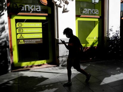 Una persona camina por el centro de Madrid delante de una sucursal de Bankia.