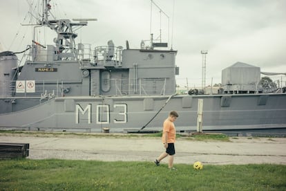 Un niño juega con una pelota frente al muelle del puerto militar de la ciudad de Liepaja.