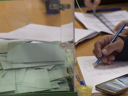 Un miembro de una mesa electoral en Sevilla consulta la aplicación de WhatsApp.