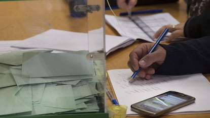 Un miembro de una mesa electoral en Sevilla consulta la aplicación de WhatsApp.