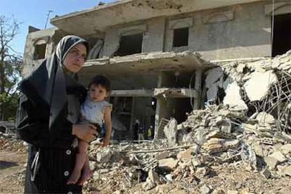 Una libanesa camina con su hija ante un edificio bombardeado en la localidad de Kafra, al sur de Líbano.