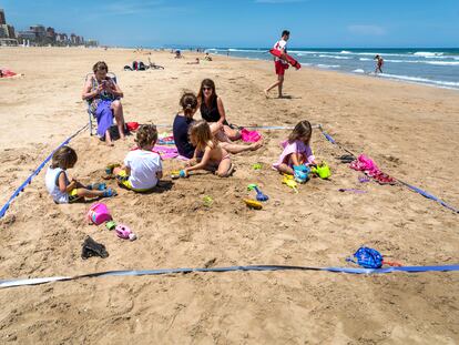 Valencia pasa a Fase 2. Dos familias que conviven en una de las parcela de prueba en la playa de Gandia.