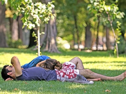 Una pareja duerme la siesta a la sombra de un árbol en el parque del Retiro en Madrid.