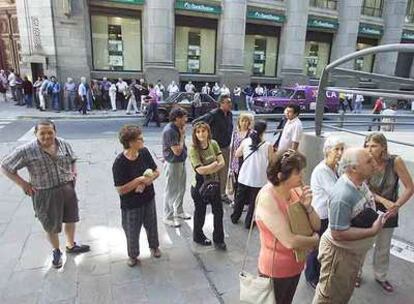 Decenas de argentinos hacen cola para entrar a un banco de Buenos Aires y recibir sus pensiones.