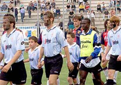 Los jugadores del Treviso entran en el estadio el domingo con varios niños y el nigeriano Omolade.