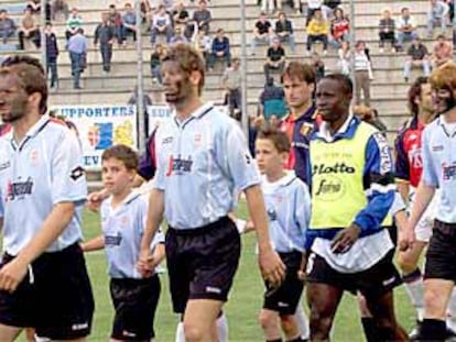 Los jugadores del Treviso entran en el estadio el domingo con varios niños y el nigeriano Omolade.