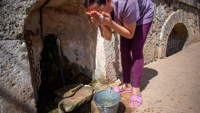 Una mujer se lava la cara con agua del grifo que hay en el exterior del manantial de El Tempul en San José del Valle (Cádiz), cuyo Ayuntamiento está enfrentado al de Jerez por su explotación