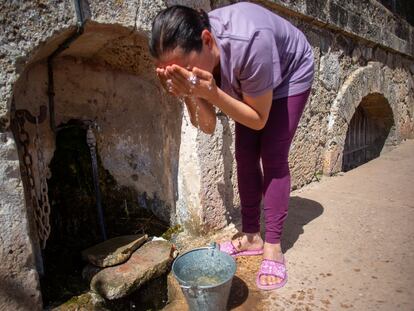 Una mujer se lava la cara con agua del grifo que hay en el exterior del manantial de El Tempul en San José del Valle (Cádiz), cuyo Ayuntamiento está enfrentado al de Jerez por su explotación
