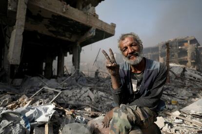 Un hombre hace el símbolo de la vitoria entre escombros de edificios destruidos en al-Hajar al-Aswad (Siria).