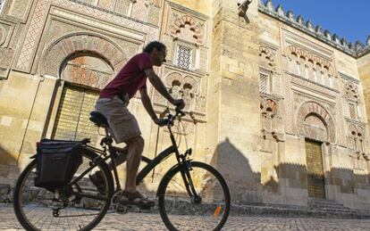 Un ciclista a su paso por la fachada oriental de la mezquita de Córdoba.