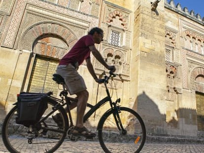 Un ciclista a su paso por la fachada oriental de la mezquita de Córdoba.