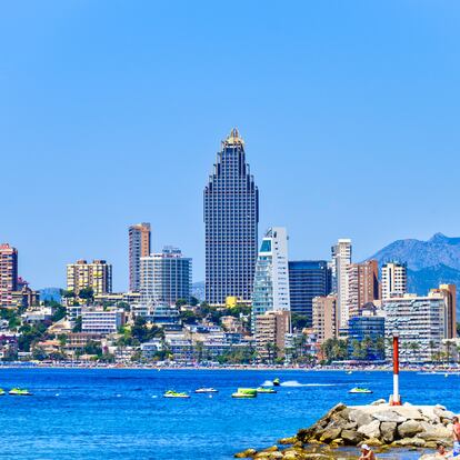 BENIDORM, ALICANTE, SPAIN - 2022/11/03: People on a rock by the beach with skyscrapers in the urban skyline of the famous city. (Photo by Roberto Machado Noa/LightRocket via Getty Images)