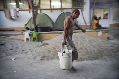 Los habitantes del campamento recogen el agua de un poco en la calle.