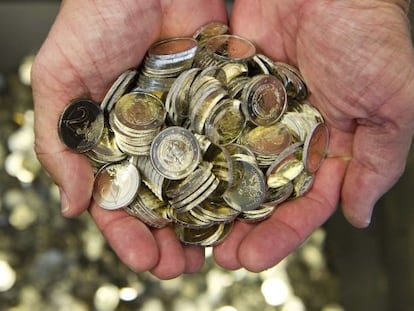 Un hombre sostiene varias monedas de euro.