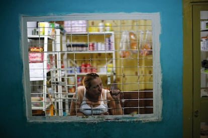 Los vecinos de la zona que rodea la torre se han quejado de frecuentes robos, atracos en cajeros automáticos y del tráfico de drogas. En la imagen, una mujer mira por la ventana de su tienda situada en uno de los pasillos de la "Torre de David. Fotografía tomada el 6 de febrero de 2014.