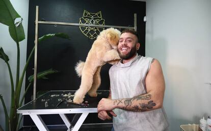 El peluquero canino Nicolás Herrero posa ante la cámara junto a un perro.