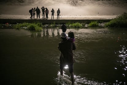 A man crosses the Rio Grande with a child in his arms, to surrender to the Border Patrol in Texas.