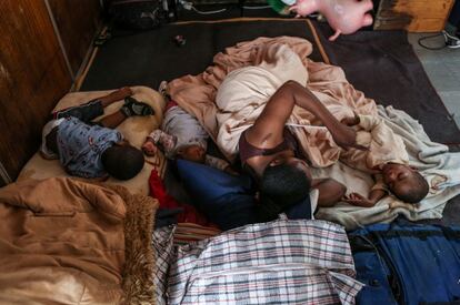 Una mujer descansa con sus tres hijos en una cama improvisada en una habitación del interior de la Iglesia metodista de Johannesburgo.