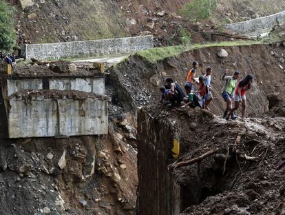 Aldeanos filipinos observan el puente dañado del municipio de Infanta por los deslizamientos de tierra y las inundaciones.