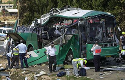 Policías israelíes inspeccionan los restos del autobús, tras el atentado en el que han muerto nueve personas.