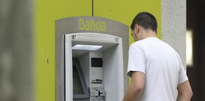 Un hombre saca dinero de un cajero automático de Bankia.